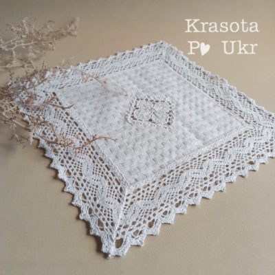 Кругла біла серветка діаметром 30 см з широким мереживом по краю, виконана з натуральної тканини.